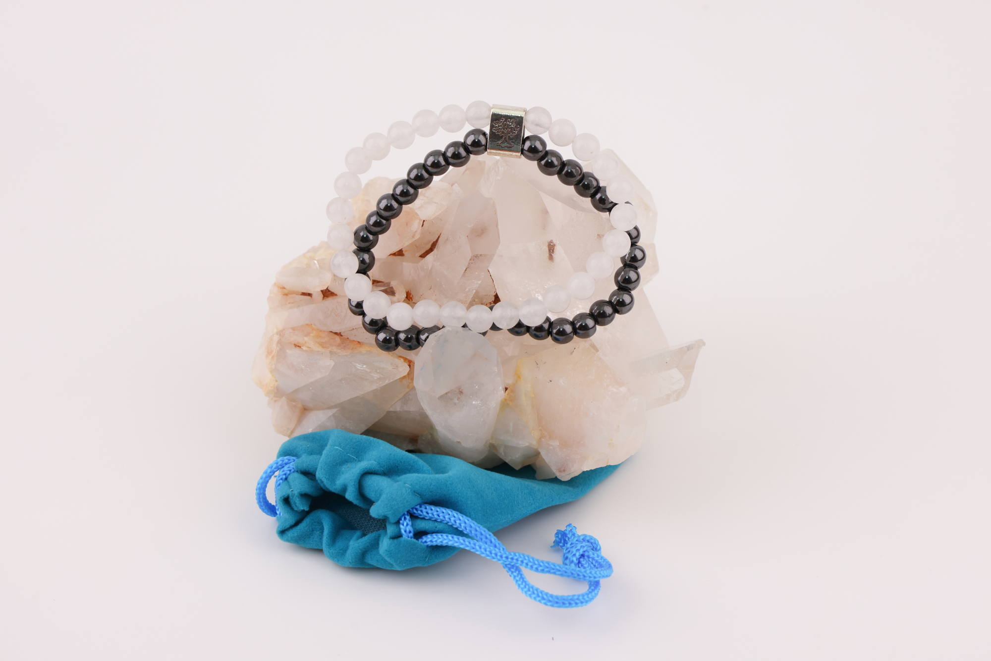 Schwarzes und weißes Magnetarmband auf Bergkristall mit blauem Schmuckbeutel.