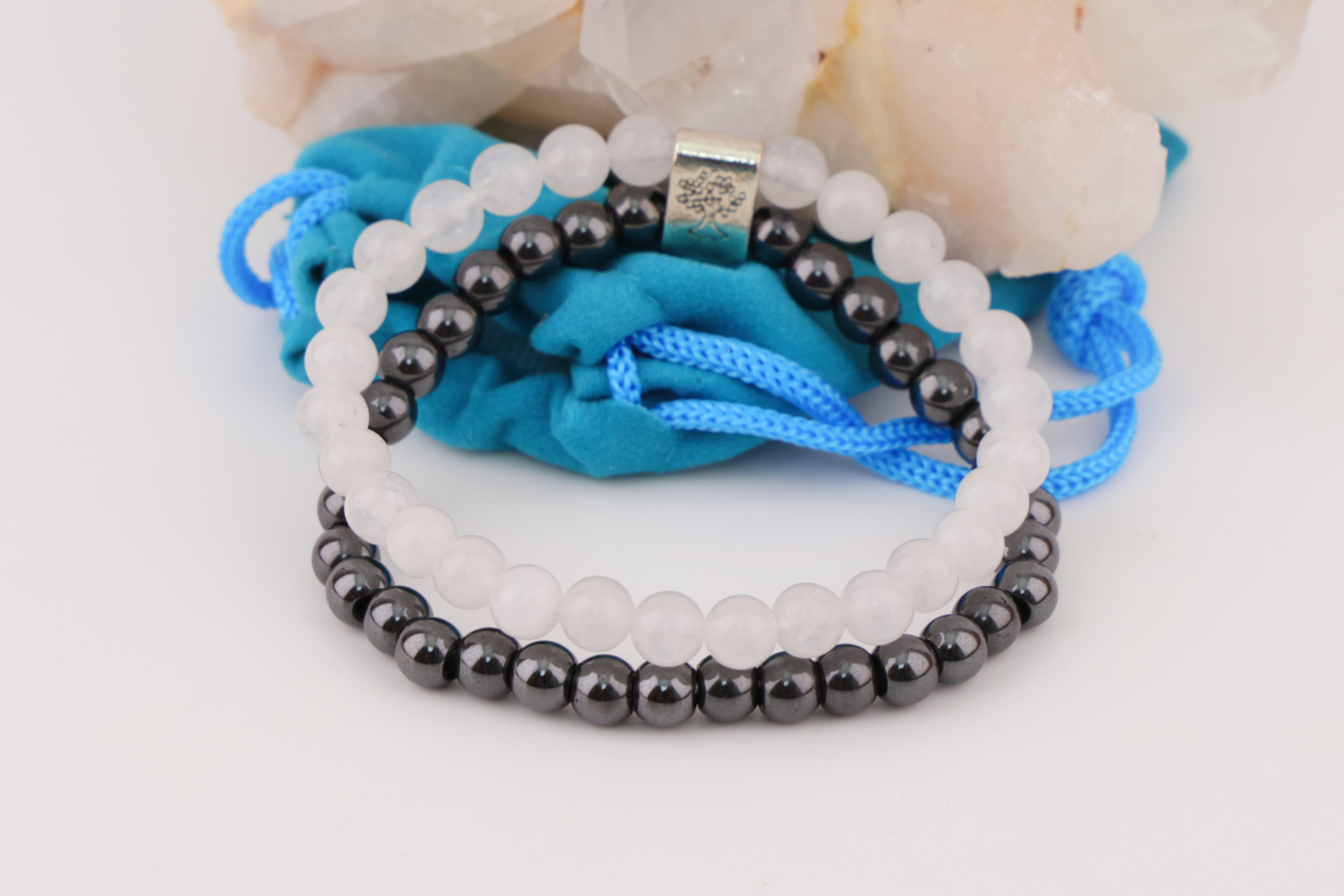 Schwarzes und weißes Magnetarmband auf Bergkristall mit blauem Schmuckbeutel.