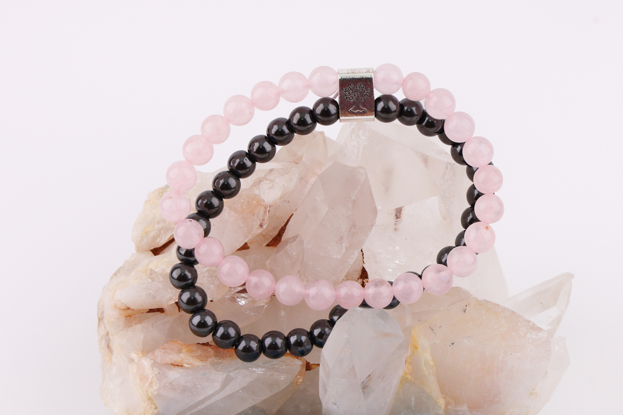 Rosenquarz‑Magnetarmband auf Rosenquarz‑Kristall mit blauem Schmuckbeutel.