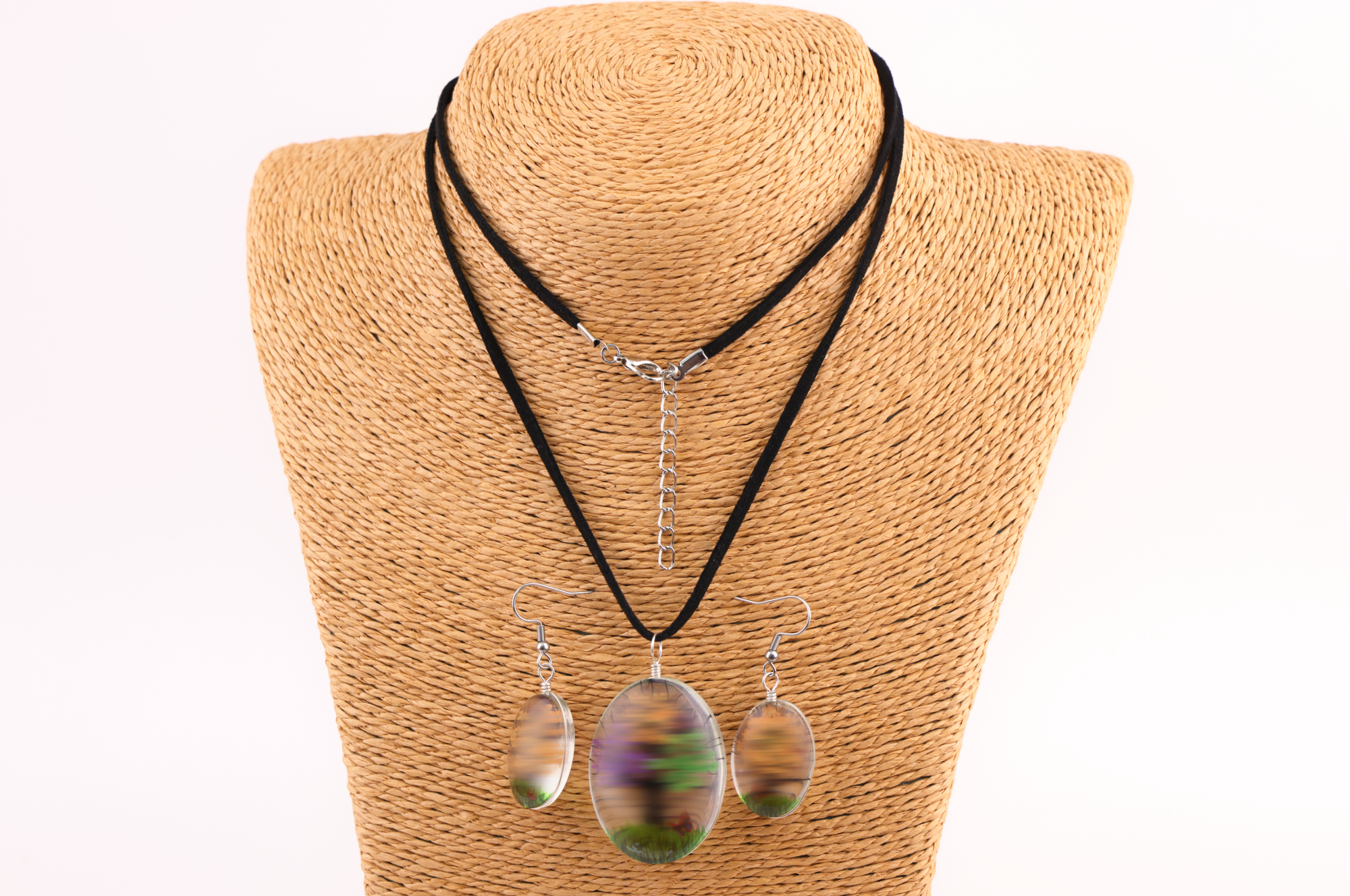 Schmuckset mit ovalem braun‑goldenem und  Anhänger sowie passenden Ohrringen, präsentiert auf einem gewebten Schmuckständer.