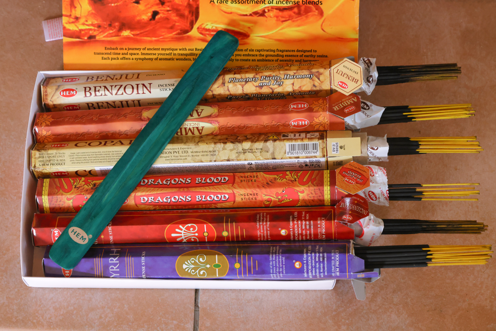HEM Räucherwerk‑Set mit großer Resin Collection Box im Hintergrund sowie mehreren Duftstäbchen‑Packungen (Myrrh, Dragon’s Blood, Copal, Benzoin, Amber) und einem türkisfarbenen Räucherstäbchenhalter im Vordergrund.