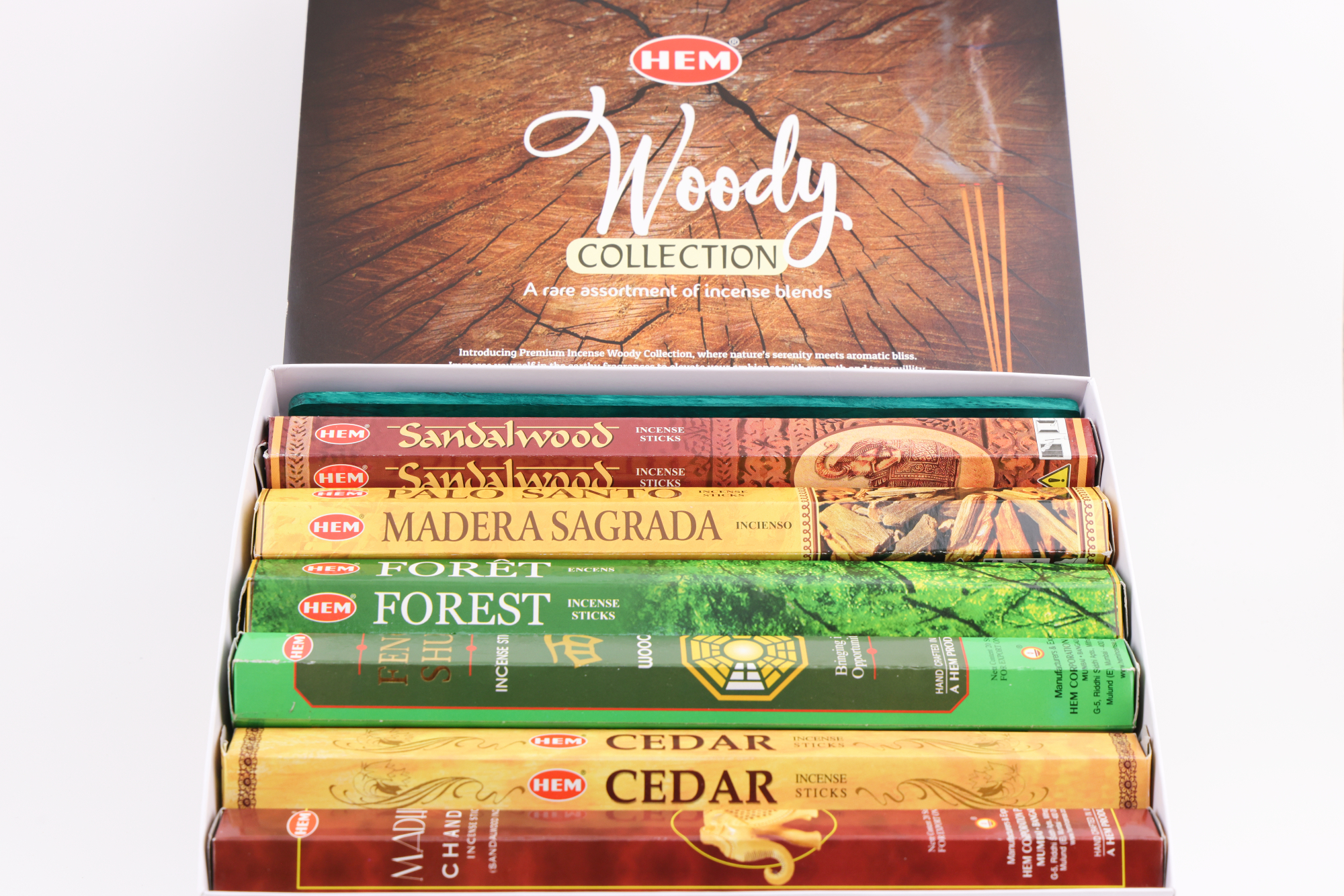 HEM Räucherwerk‑Set der Woody Collection mit verschiedenen Duftstäbchen‑Packungen (Cedar, Palo Santo, Foret, Feng Shui, Sandal), gelben Räucherstäbchen und grünem Halter.